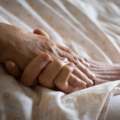 Eine Frau hält die Hand einer Pflegebedürftigen