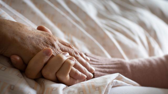 Eine Frau hält die Hand einer Pflegebedürftigen