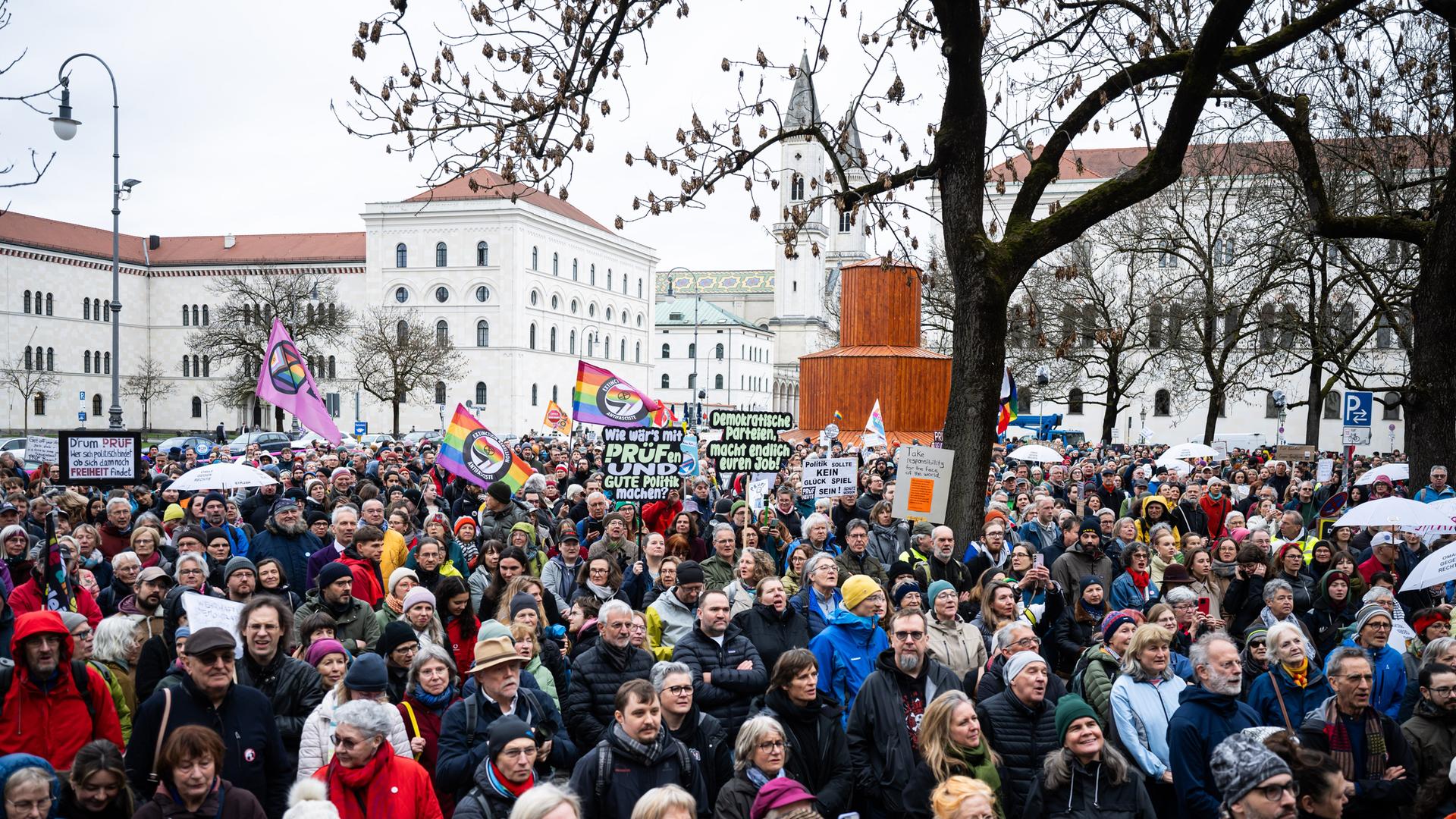 Teilnehmer der Demo für die Überprüfung rechtsextremer Parteien durch das Bundesverfassungsgericht stehen mit Plakaten und Schildern auf dem Geschwister-Scholl-Platz in München.