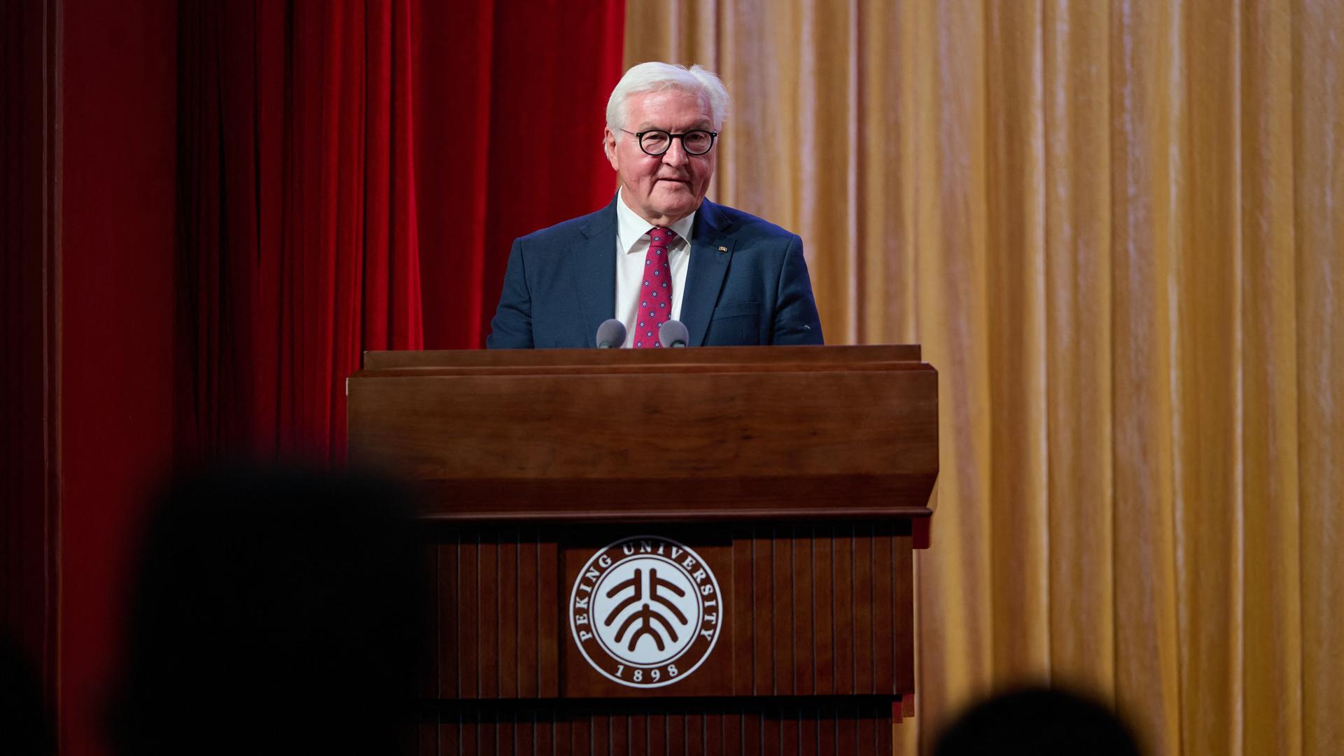 Bundespräsident Frank-Walter Steinmeier steht in einer Aula der Peking Universität an einem Rednerpult und spricht. Dahinter ein Faltenvorhang. Bundespräsident Frank-Walter Steinmeier steht in einer Aula der Peking Universität an einem Rednerpult und spricht. Dahinter ein Faltenvorhang.