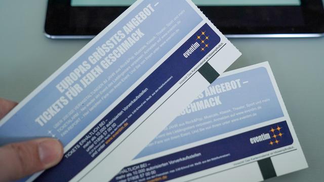 Eine Hand hält zwei Konzert-Karten. 