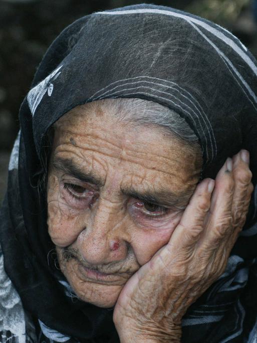 Elena Gardashyan, 97, die älteste Einwohnerin von Kirants in der armenischen Provinz Tawusch. Sie hat eine Hand auf ihre Wange gelegt, trägt ein Kopftuch und schaut resigniert schräg auf den Boden.