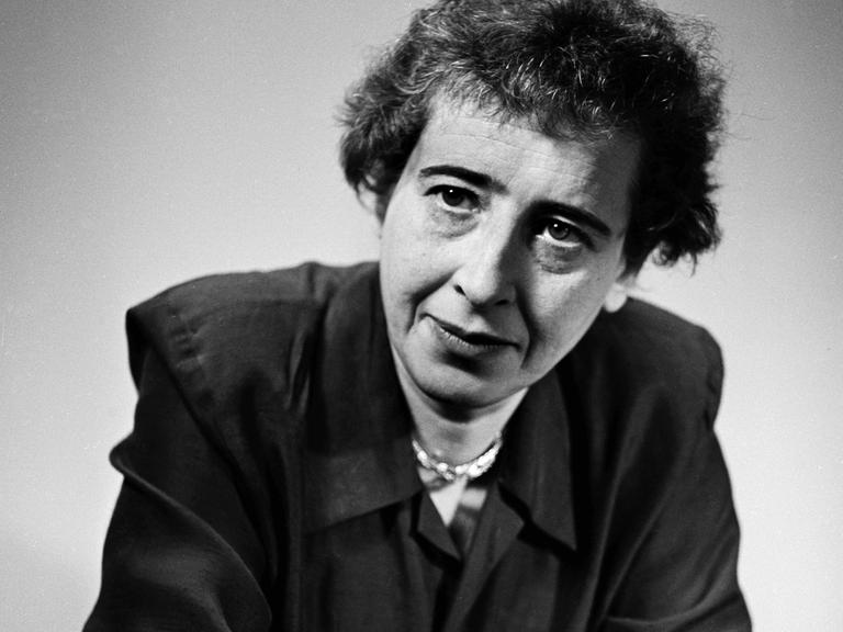 Schwarzweißaufnahme von Hannah Arendt in legerer Pose, die lakonisch ins Off schaut