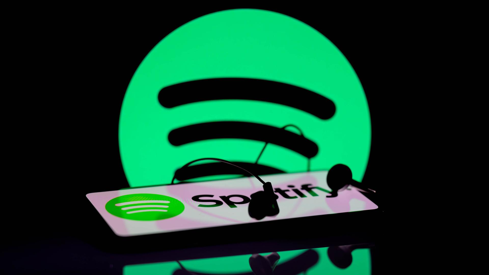 Das Spotify-App wird auf einem Smartphone angezeigt. Im Hintergrund ist das Spotify-Symbol zu sehen.