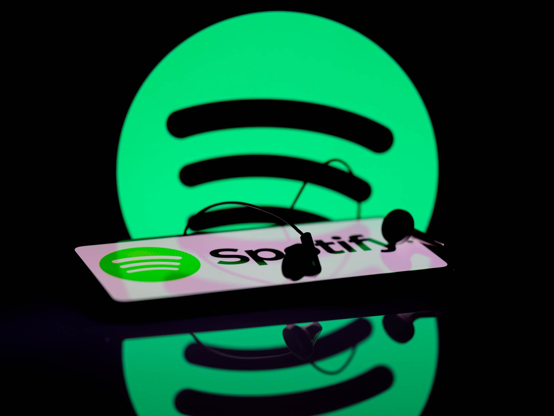 Das Spotify-App wird auf einem Smartphone angezeigt. Im Hintergrund ist das Spotify-Symbol zu sehen.