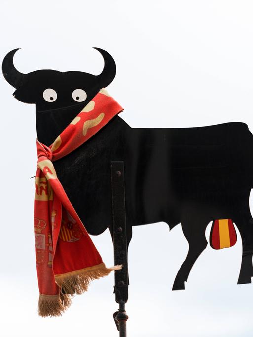 Darstellung eines schwarzen Stiers mit Hodensack in den spanischen Nationalfarben.
