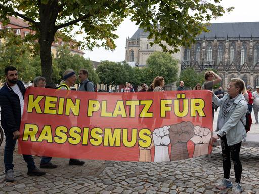 Migranten protestieren in Magdeburg gegen die AfD. Zu sehen ist ein großes Plakat, auf dem steht: "Kein Platz für Rassismus".