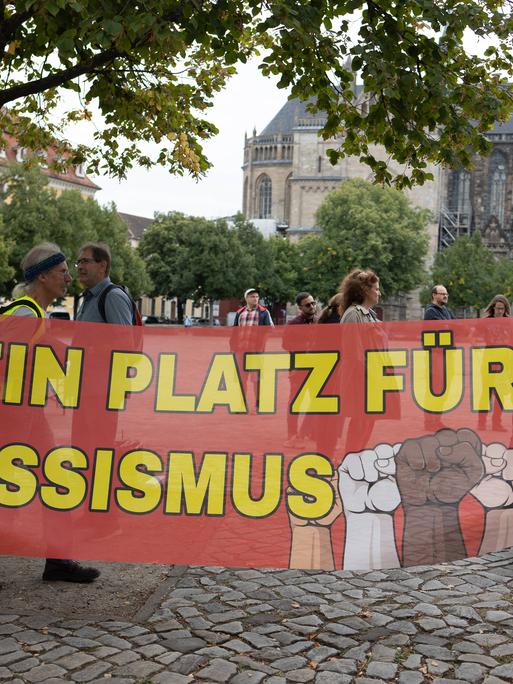 Migranten protestieren in Magdeburg gegen die AfD. Zu sehen ist ein großes Plakat, auf dem steht: "Kein Platz für Rassismus".