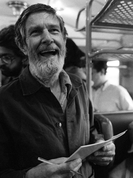 Der Komponist John Cage mit Paier in der Hand im Zug nach Bologna