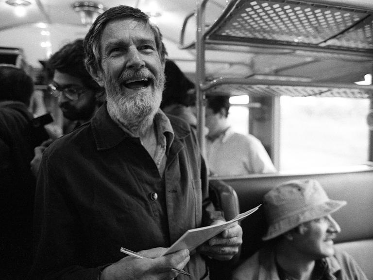Der Komponist John Cage mit Paier in der Hand im Zug nach Bologna