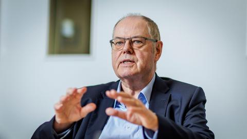 Peer Steinbrück, Bundesminister a.D., SPD, gestikuliert während eines Interviews mit den Händen, im Hintergrund sieht man verschwommen ein Bild an der Wand.