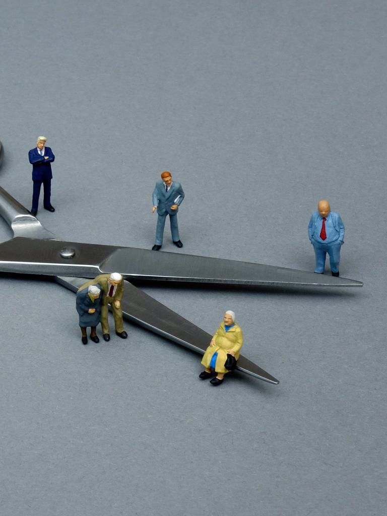 Ein Symbolbild zeigt um eine Schere gruppierte kleine Figuren, um so die Teilung der Gesellschaft zu veranschaulichen.