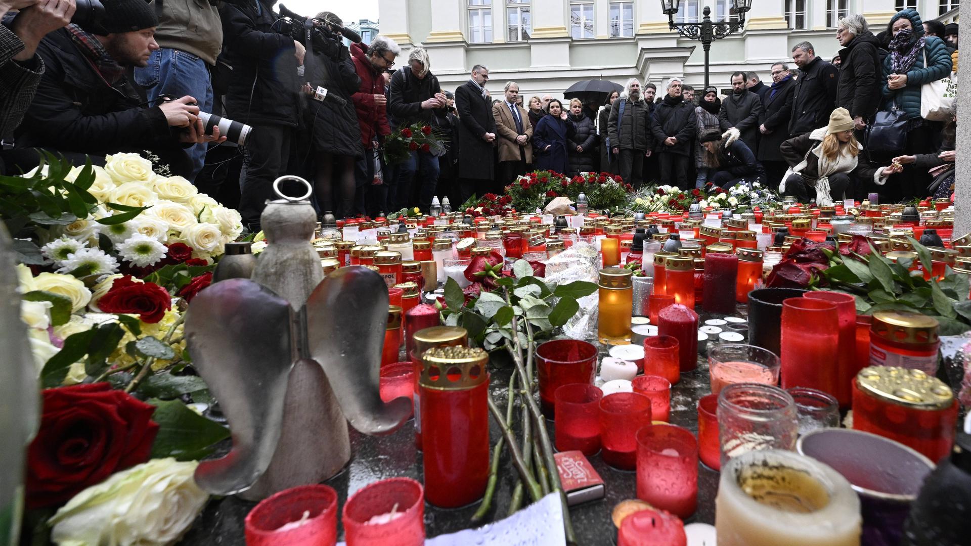 Viele Menschen stehen in Gedenken an die Toten und Verletzten in Prag vor der Universität um die vielen Kerzen und Blumen.