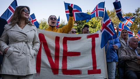 Menschen halten Island-Flaggen sowie ein großes Plakat mit der Aufschrit "Nei" 