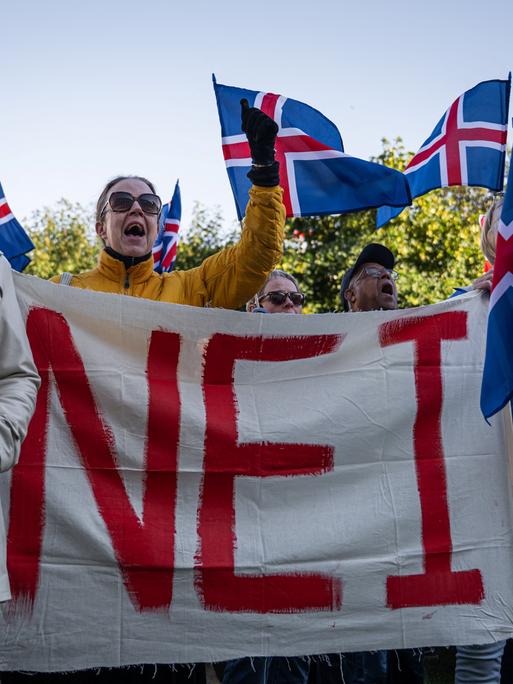 Menschen halten Island-Flaggen sowie ein großes Plakat mit der Aufschrit "Nei" Menschen halten Island-Flaggen sowie ein großes Plakat mit der Aufschrit "Nei"