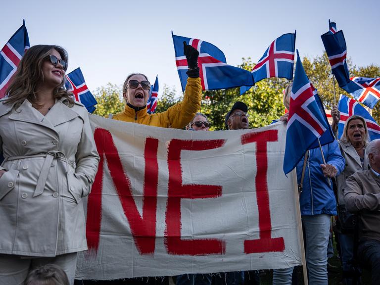 Menschen halten Island-Flaggen sowie ein großes Plakat mit der Aufschrit "Nei" Menschen halten Island-Flaggen sowie ein großes Plakat mit der Aufschrit "Nei"