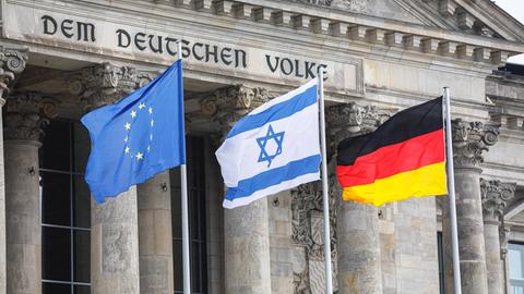 Die Israelische Fahne zwischen der deutschen und der europäischen Flagge vor dem Reichstag 