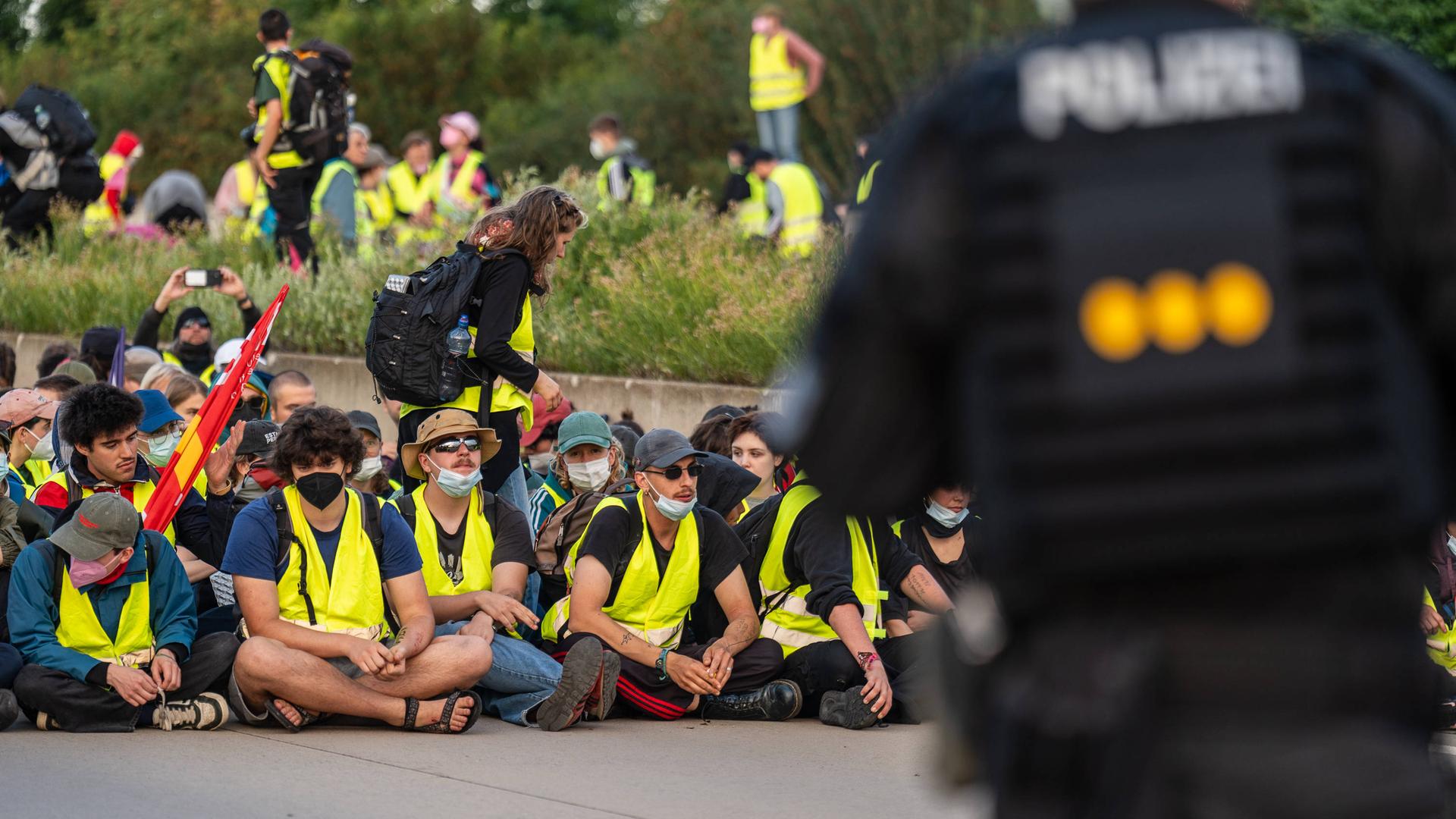 Das Aktionsbündnis "Widersetzen" bei einer gewaltfreie Sitzblockaden an den Zufahrtswegen zur Messe in Erfurt, in der der AfD-Bundesparteitag stattfindet. Die Demonstranten tragen gelbe Warnwesten, ein Polizist steht im Vordergrund. Das Aktionsbündnis "Widersetzen" bei einer gewaltfreie Sitzblockaden an den Zufahrtswegen zur Messe in Erfurt, in der der AfD-Bundesparteitag stattfindet. Die Demonstranten tragen gelbe Warnwesten, ein Polizist steht im Vordergrund.