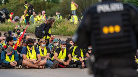 Das Aktionsbündnis "Widersetzen" bei einer gewaltfreie Sitzblockaden an den Zufahrtswegen zur Messe in Erfurt, in der der AfD-Bundesparteitag stattfindet. Die Demonstranten tragen gelbe Warnwesten, ein Polizist steht im Vordergrund.