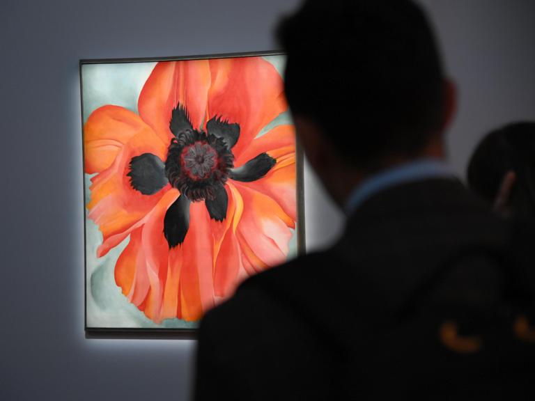 Gemälde einer Mohnblume, mit Blättern in rot leuchtenden Tönen, im Vordergrund die dunkle Silhouette eines Museumsgastes