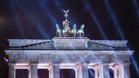 Lichstrahlen leuchten vor dem dunklen Himmel und der Quadriga am Brandenburger Tor.