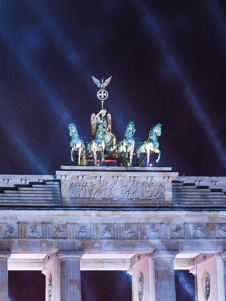 Lichstrahlen leuchten vor dem dunklen Himmel und der Quadriga am Brandenburger Tor.