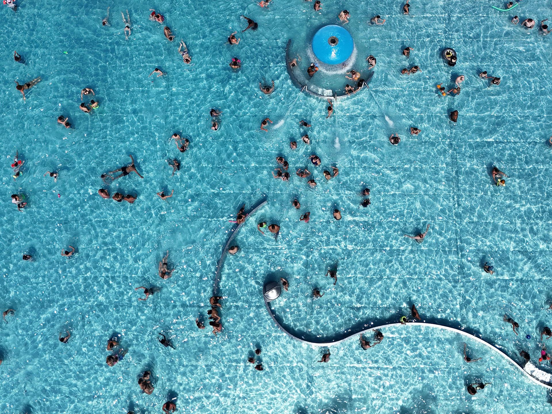 Blick von oben auf das Michaelibad in München, wo Besucher in einem großen Schwimmbecken schwimmen.