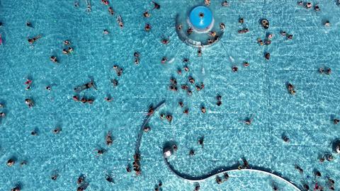 Blick von oben auf das Michaelibad in München, wo Besucher in einem großen Schwimmbecken schwimmen.