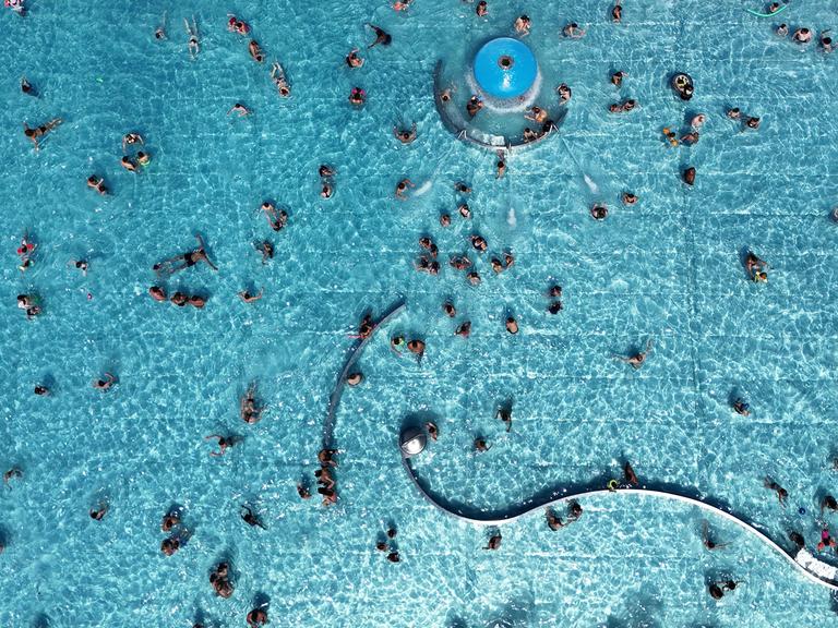 Blick von oben auf das Michaelibad in München, wo Besucher in einem großen Schwimmbecken schwimmen.