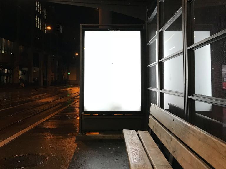 Eine leere weiße Werbetafel an einer Bushaltestelle.