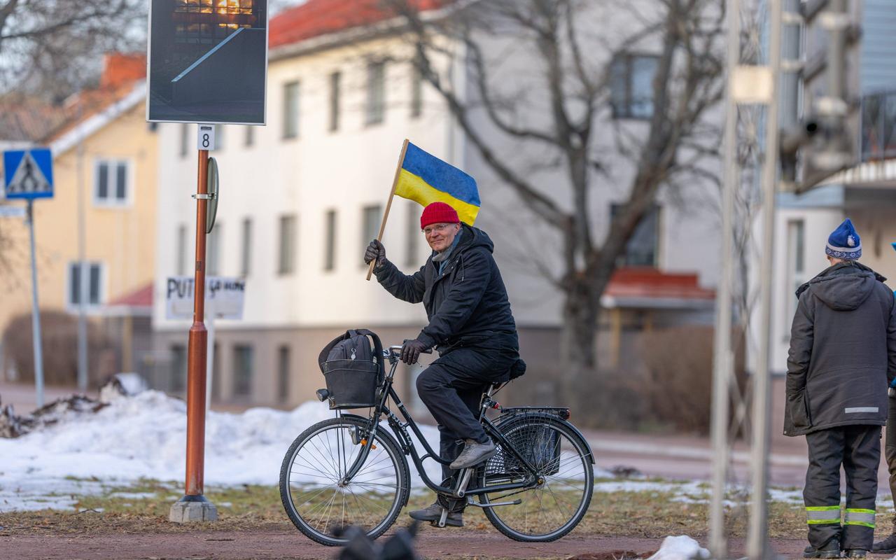 Ein Mann auf dem Fahrrad hält die ukrainische Flagge in der Hand.