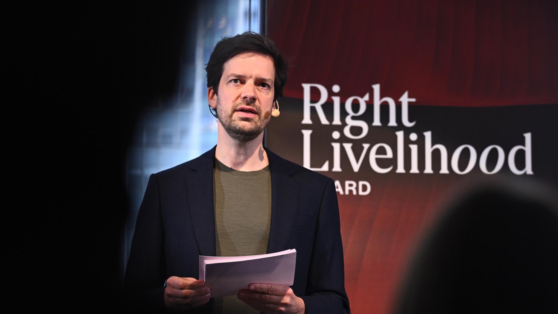 Ole von Uexküll steht an einem Redepult. Er trägt ein Headset. Im Hintergrund ein Poster mit der Aufschrift "Right Livelihood Award".