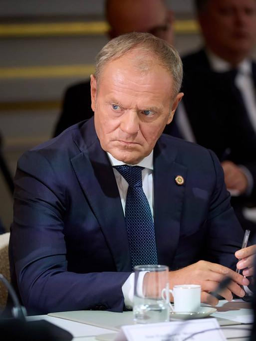 Der polnische Premierministier Donald Tusk sitzt mit weiteren Menschen an einem Konferenztisch.