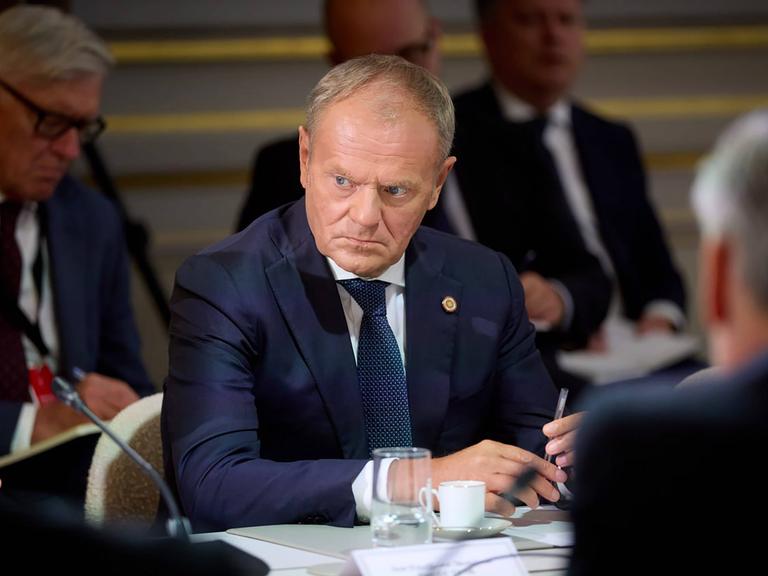 Der polnische Premierministier Donald Tusk sitzt mit weiteren Menschen an einem Konferenztisch.