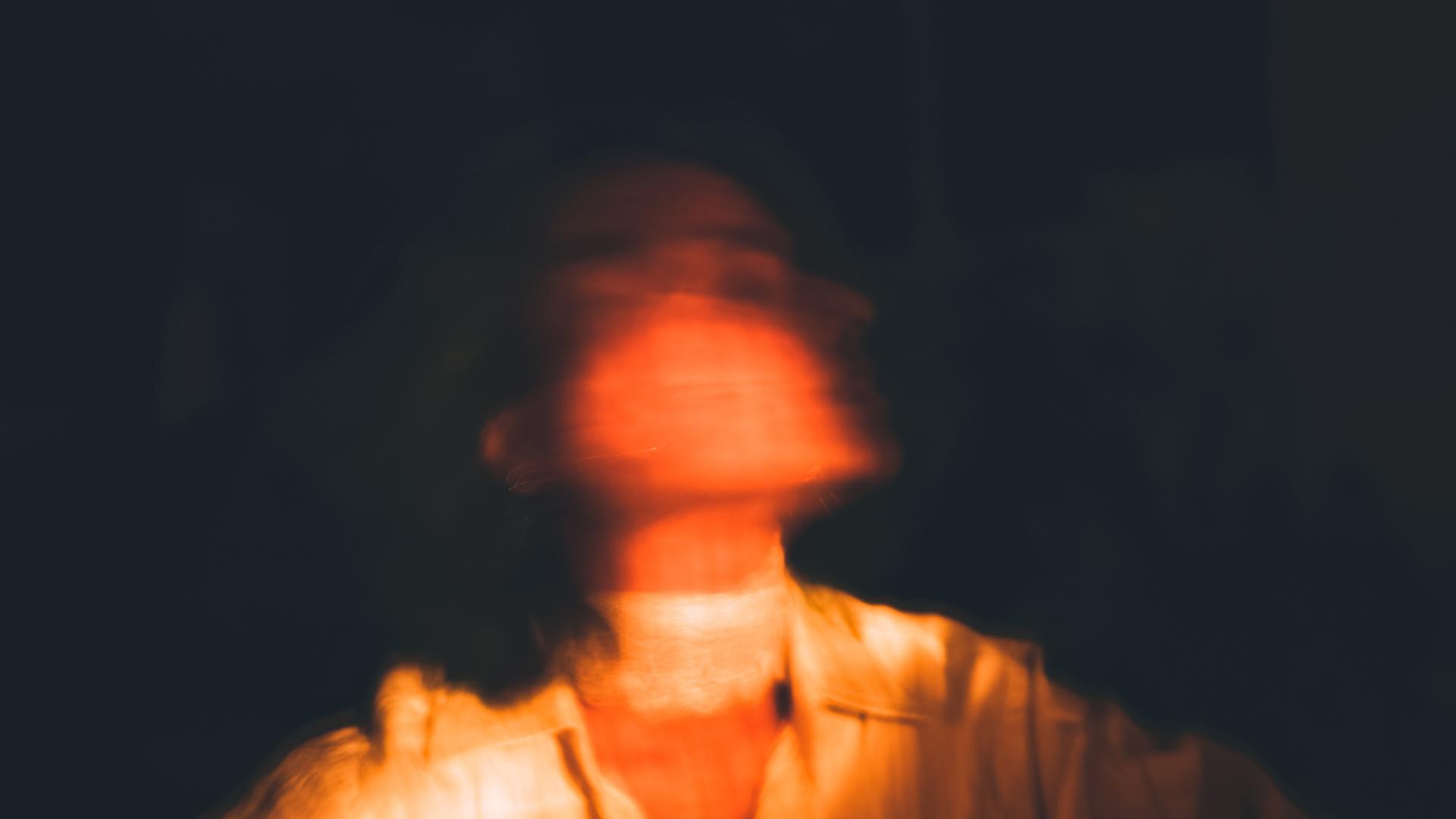 Verschwommene Darstellung einer Frau vor dunklem Hintergrund