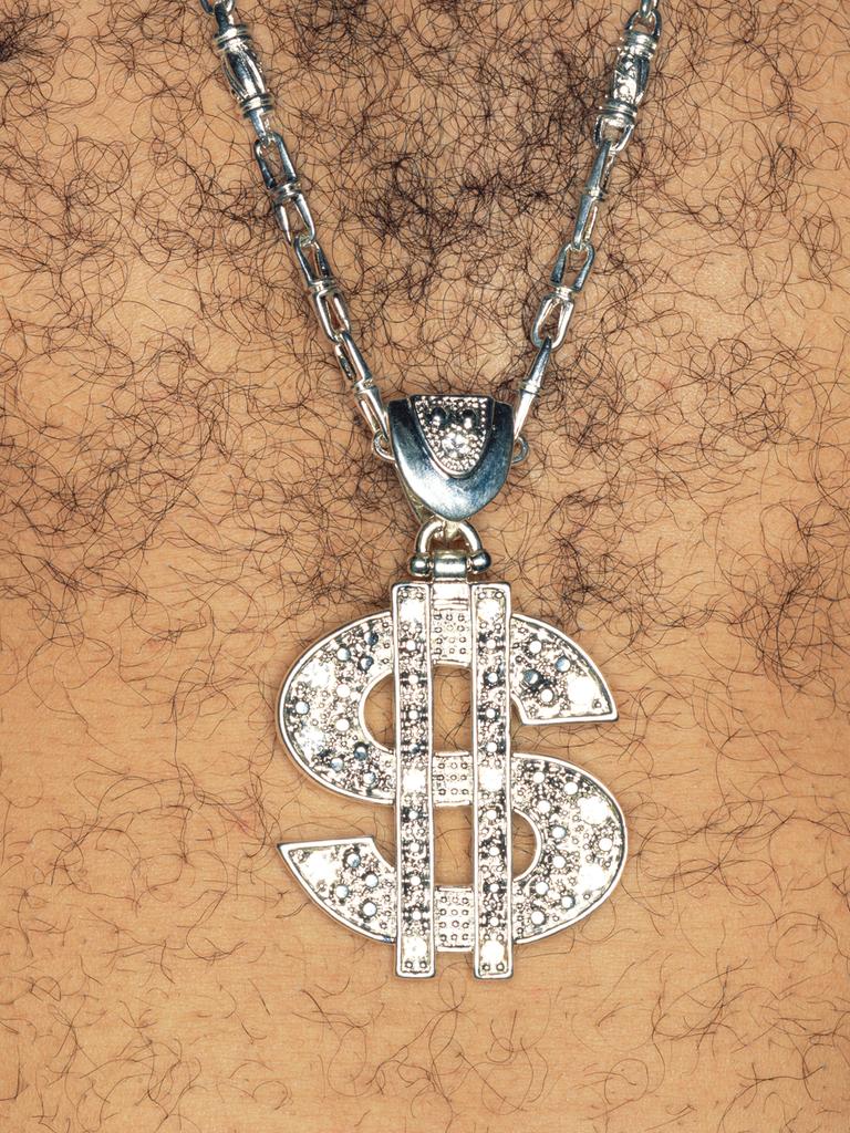 Ein Mann mit behaarter Brust, der ein glitzernde Kette mit einem US-Dollar-Zeichen als Anhänger trägt.
