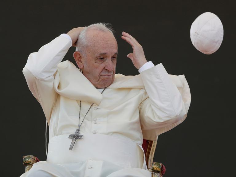 Ein Windstoß weht die Kappe, den Pileolus, von Papst Franziskus weg.