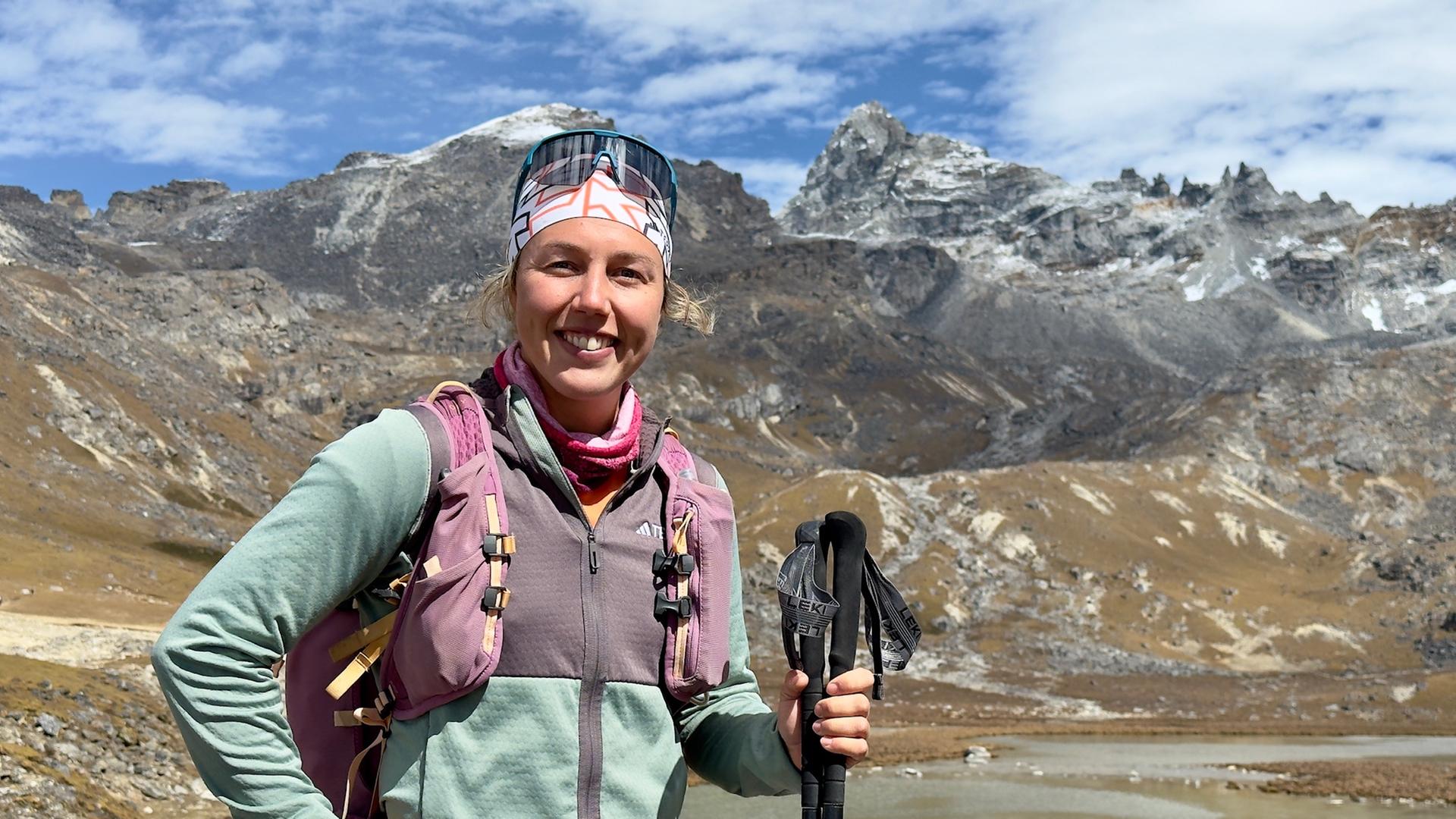 Laura Dahlmeier steht im Wanderoutfit vor einer Bergkulisse.