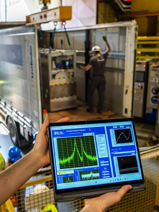 Ein Wissenschaftler am CERN zeigt einen Bildschirm, auf dem Antimateriemenge zu sehen ist in Form von Kurven. Im Hintergrund wird eine Box in einen LKW eingeladen. Europäische Organisation für Kernforschung in Genf im März 2026 Ein Wissenschaftler am CERN zeigt einen Bildschirm, auf dem Antimateriemenge zu sehen ist in Form von Kurven. Im Hintergrund wird eine Box in einen LKW eingeladen. Europäische Organisation für Kernforschung in Genf im März 2026