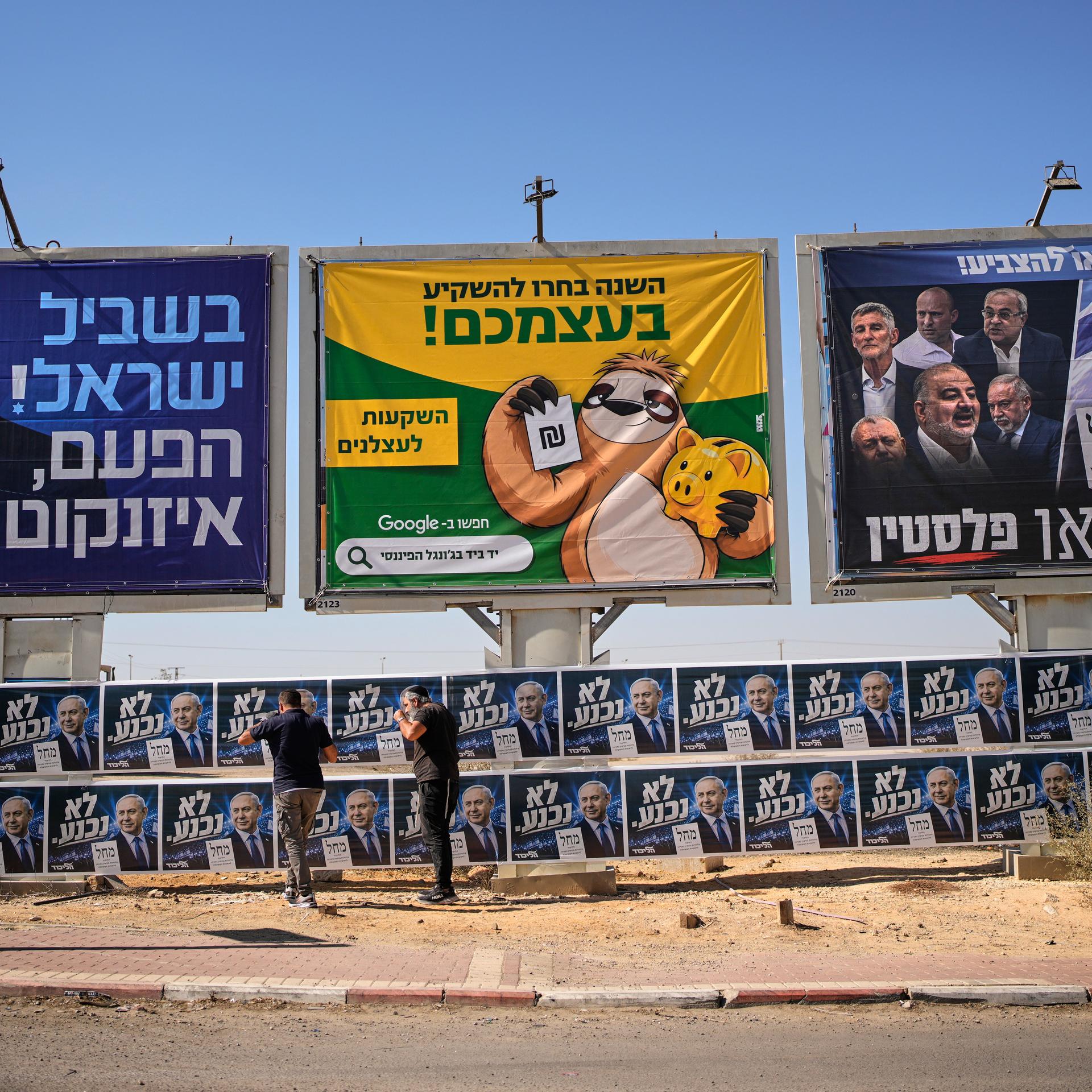 Israel, Dimona: Likud-Aktivisten hängen im Vorfeld der israelischen Parlamentswahlen Wahlplakate des israelischen Ministerpräsidenten Netanjahu neben einer Werbetafel mit dem Oppositionskandidaten Eisenkot auf. 