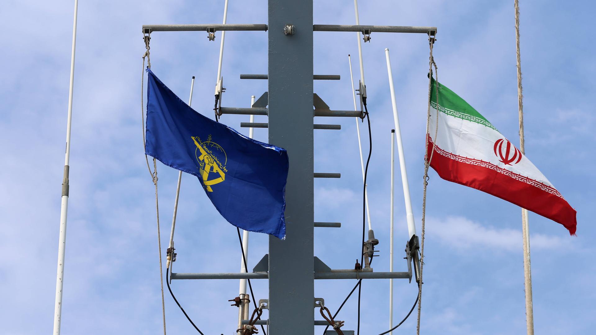 Die Flaggen des Schiffs wehen im Wind. Es sind die iranische Nationalflagge und die Flagge der iranischen Revolutionsgarden. 