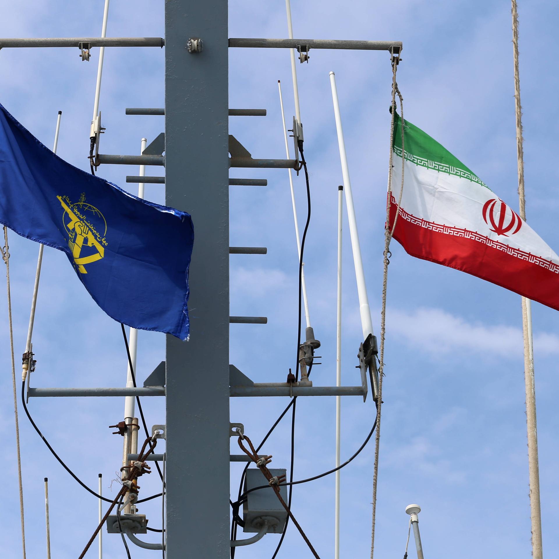 Die Flaggen des Schiffs wehen im Wind. Es sind die iranische Nationalflagge und die Flagge der iranischen Revolutionsgarden. 