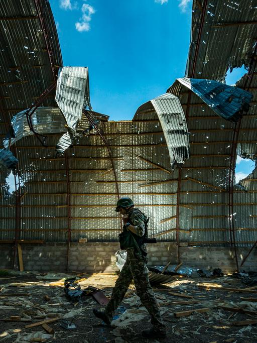 Ein ukrainischer Soldat läuft durch einen halb zerstörten Getreidespeicher.