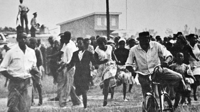 Schwarze Menschen fliehen zu Fuß oder auf dem Fahrrad vor der Polizei. Die Demonstranten versammelten sich am 21. März vor dem Polizeirevier des Townships Sharpeville, etwa 50 Kilometer südlich von Johannesburg, um gegen die Passgesetze zu demonstrieren.