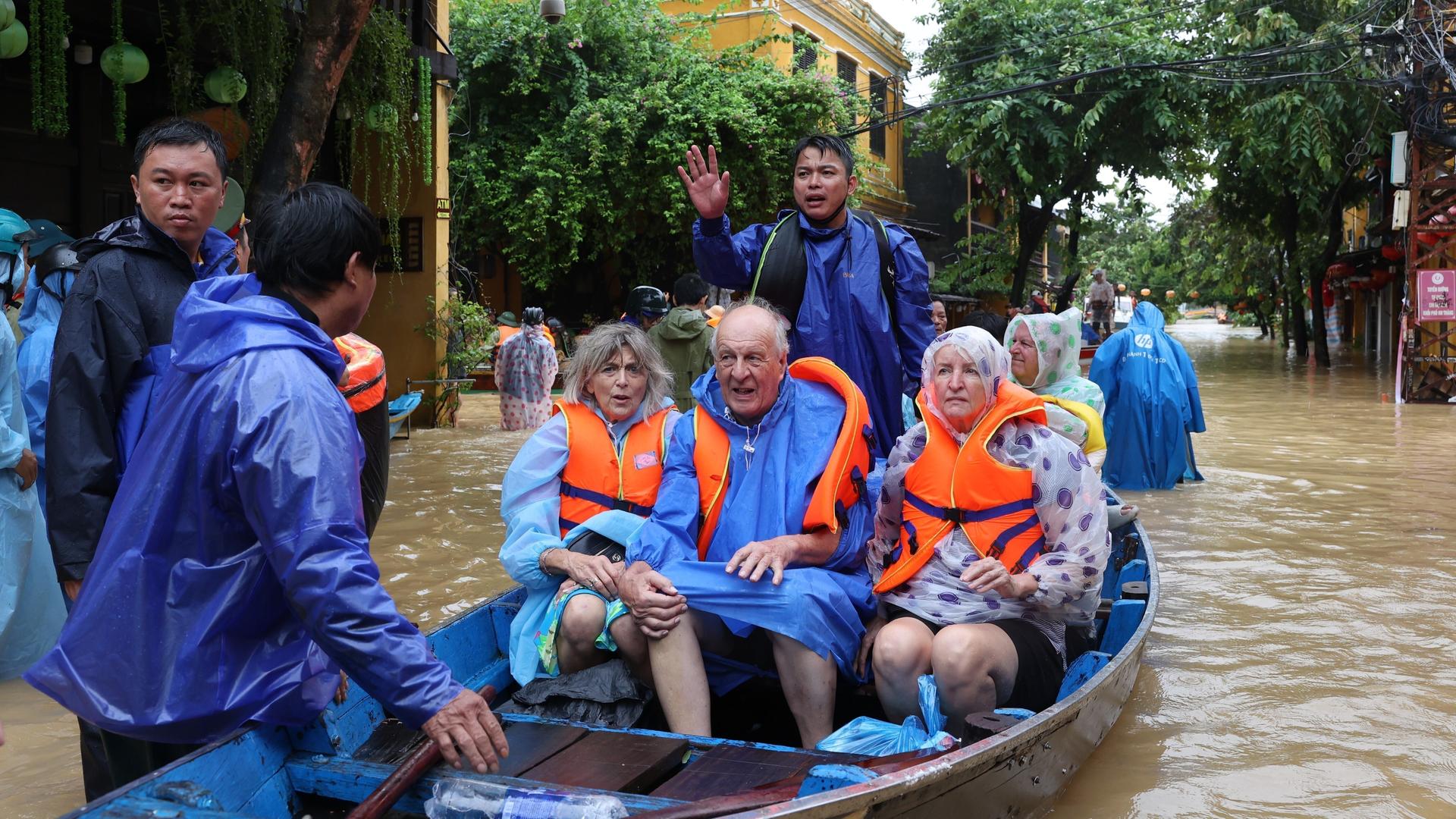 Touristen werden mit einem Boot aus den Fluten in Vietnam evakuiert. Nach Rekordregenfällen in Vietnam stehen viele Straßen unter Wasser.