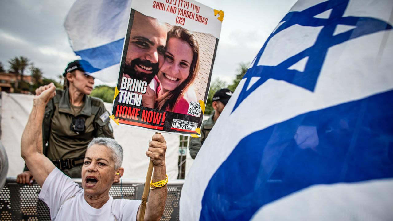 Eine Frau hält im Juni 2024 im israelischen Caesarea ein Plakat mit den damals noch verschleppten Geiseln Yarden und Shiri Bibas in die Luft, neben ihr werden Israel-Flaggen geschwenkt.   