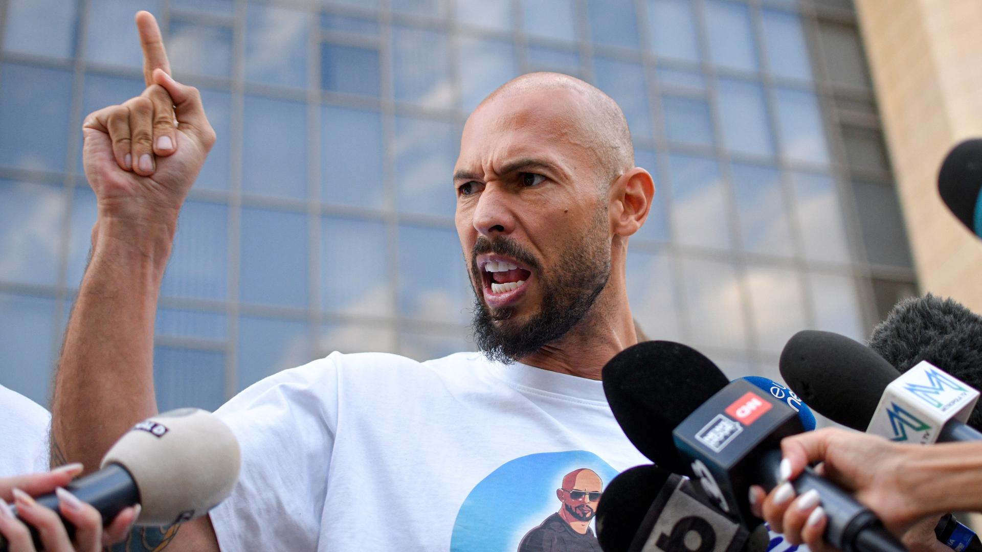 Andrew Tate gestikuliert wild vor Pressevertretern. Im Hintergrund ist ein Gerichtsgebäude zu sehen Andrew Tate gestikuliert wild vor Pressevertretern. Im Hintergrund ist ein Gerichtsgebäude zu sehen