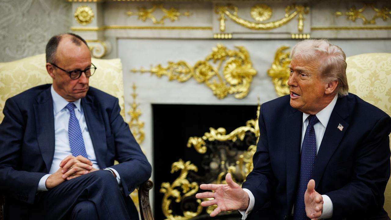 Bundeskanzler Friedrich Merz sitzt neben US-Präsident Donald Trump, der gerade spricht und gestikuliert, in goldenen Sesseln vor einem goldbeschlagenen Kamin im Oval Office im Weißen Haus in Washington.  