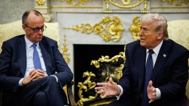 Bundeskanzler Friedrich Merz sitzt neben US-Präsident Donald Trump, der gerade spricht und gestikuliert, in goldenen Sesseln vor einem goldbeschlagenen Kamin im Oval Office im Weißen Haus in Washington. 