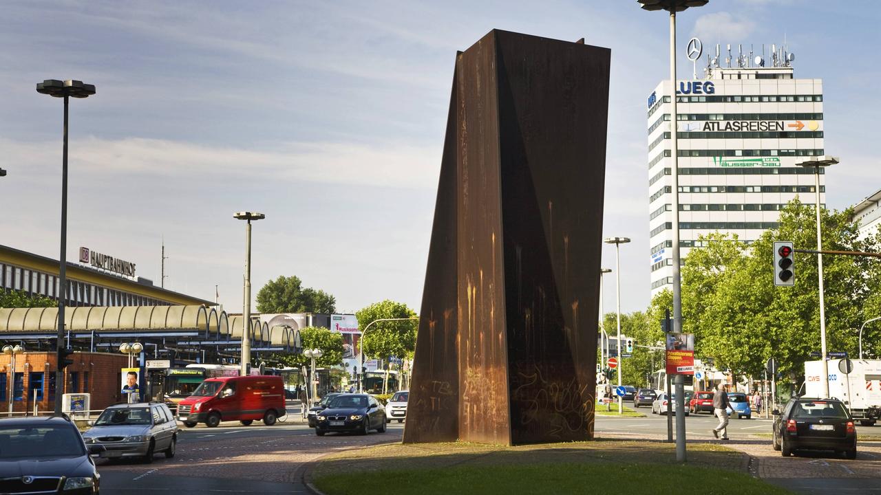 Eine große Skulptur aus rostendem Stahl steht in Bochum nahe dem Hauptbahnhof.